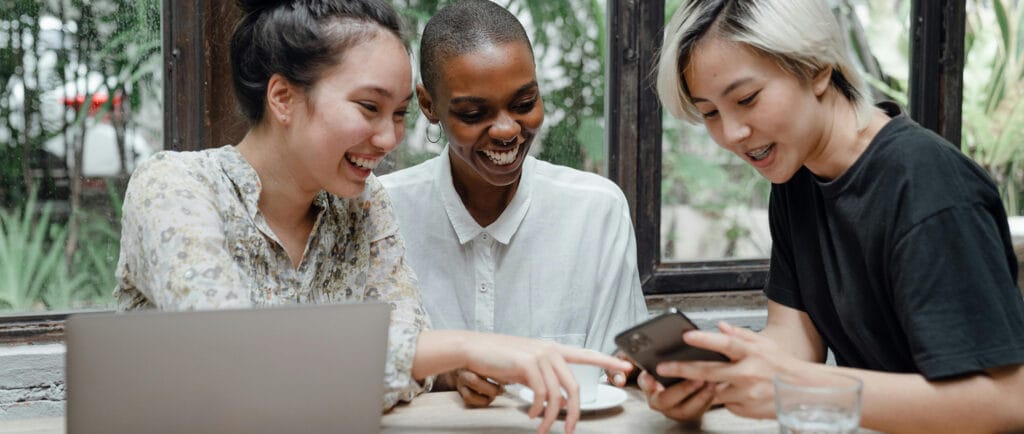 Three young women in business casual attire networking and connecting at annual conference. 